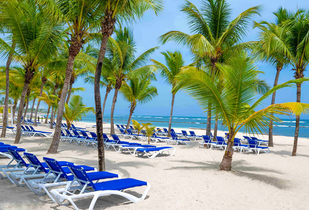 Tumbonas azules sobre la playa del Resort Coral Costa Caribe en Juan Dolio República Dominicana