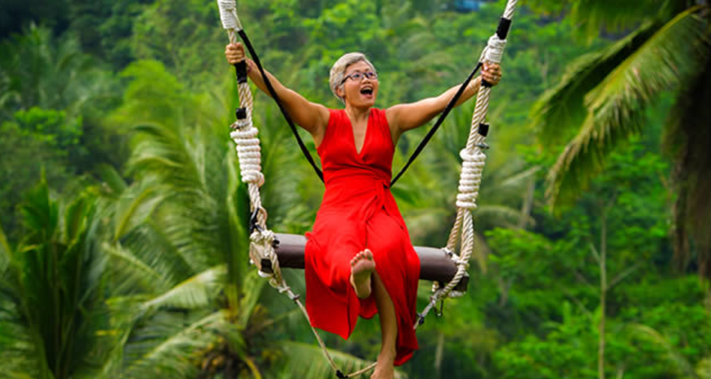 Mujer con vestido rojo se columpia sobre la selva panameña